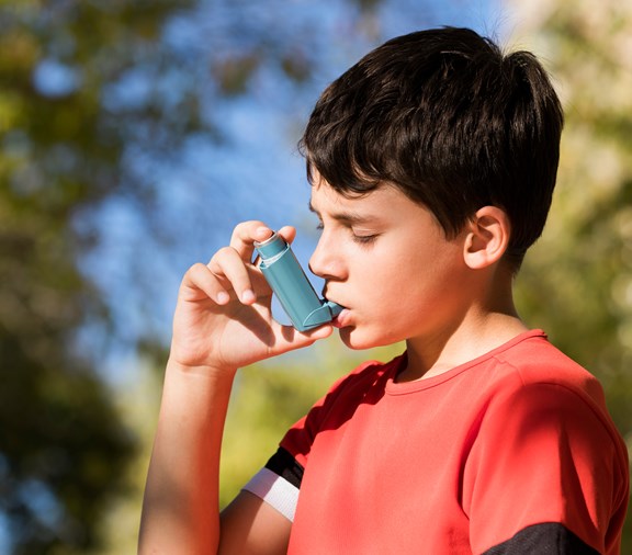 Young boy using inhaler after asthma trigger