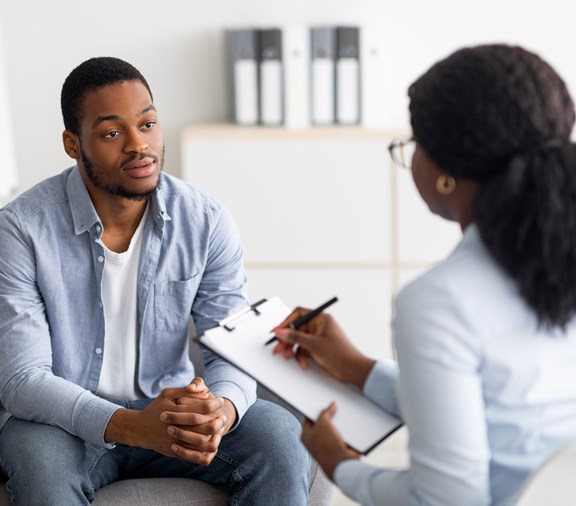 Unhappy young black man having session with mental health professional at behavioral health clinic